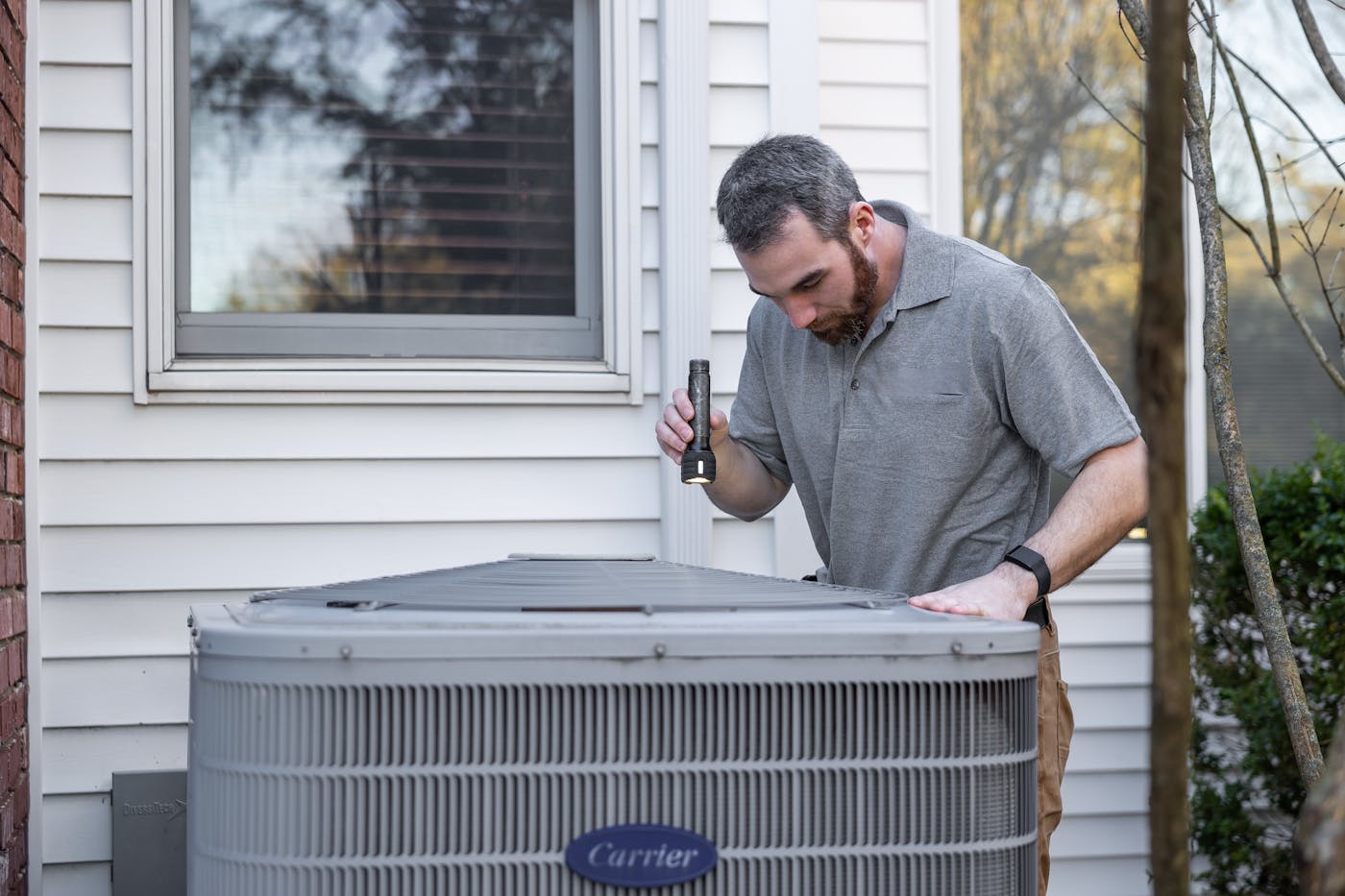 HVAC technician inspecting an outdoor condenser for AC repair in Moore OK