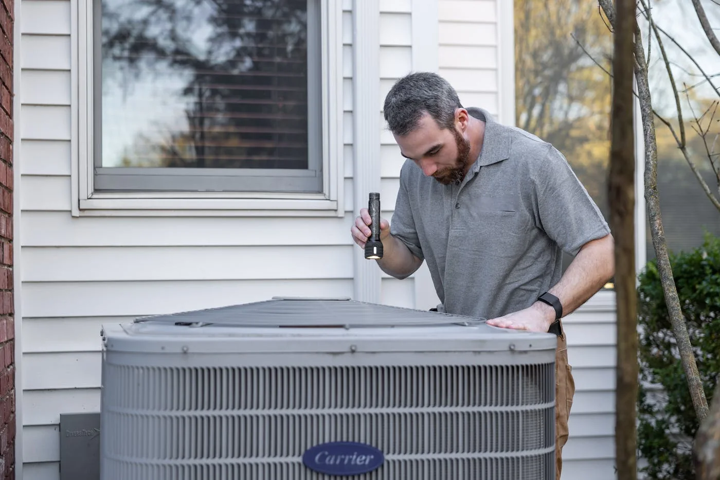 HVAC technician inspecting an outdoor condenser for AC repair in Moore OK