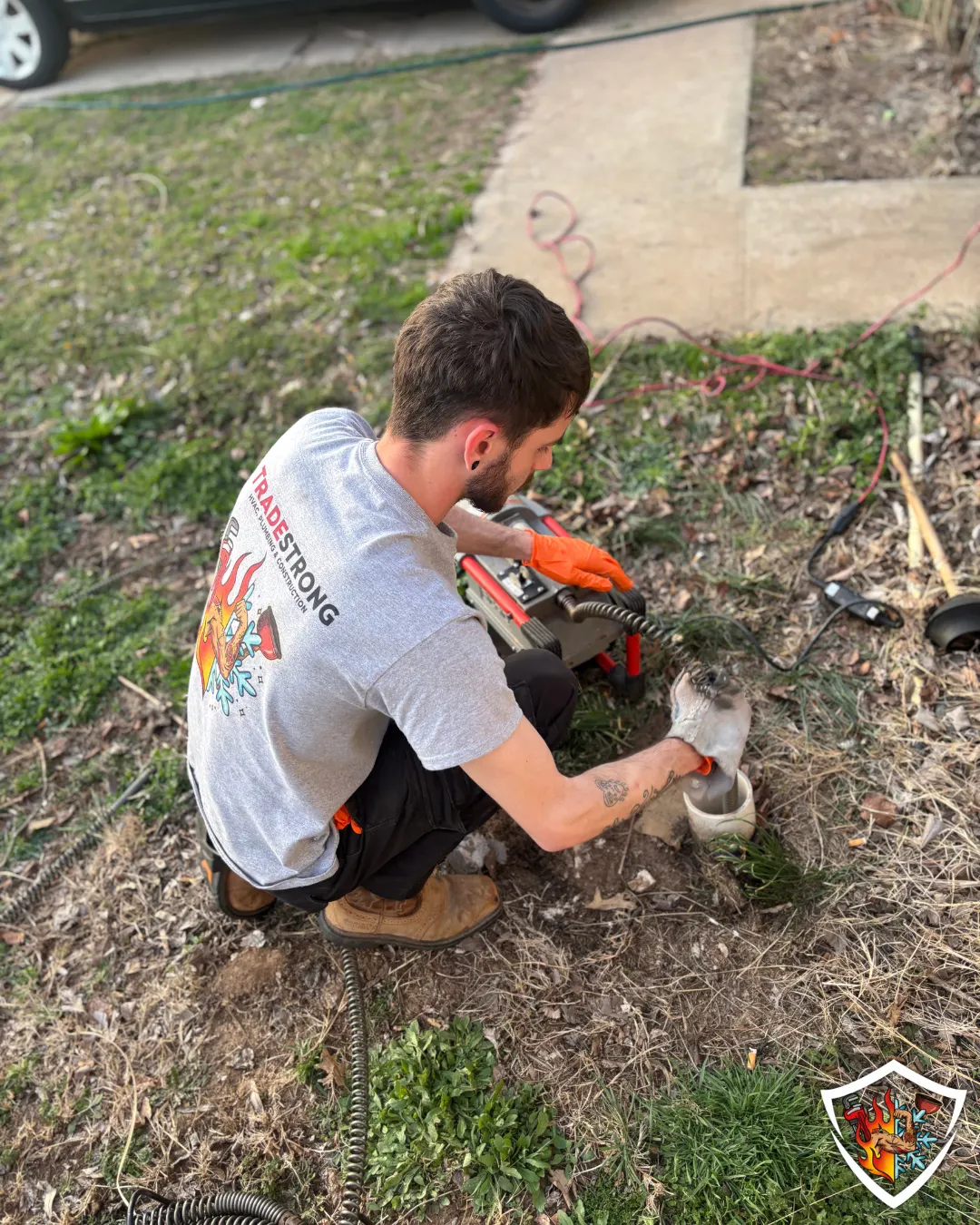 TradeStrong plumber clearing an outdoor drain line in a Moore home