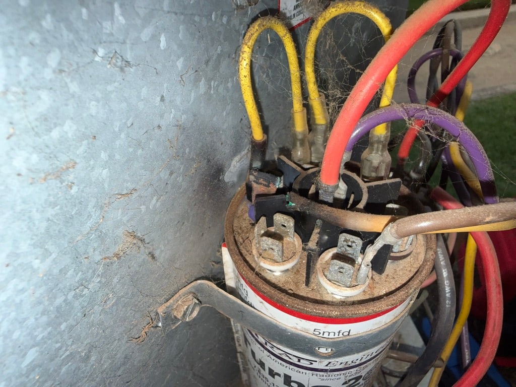 Burned wire and weathered electrical components inside an older Norman air conditioner during TradeStrong HVAC service