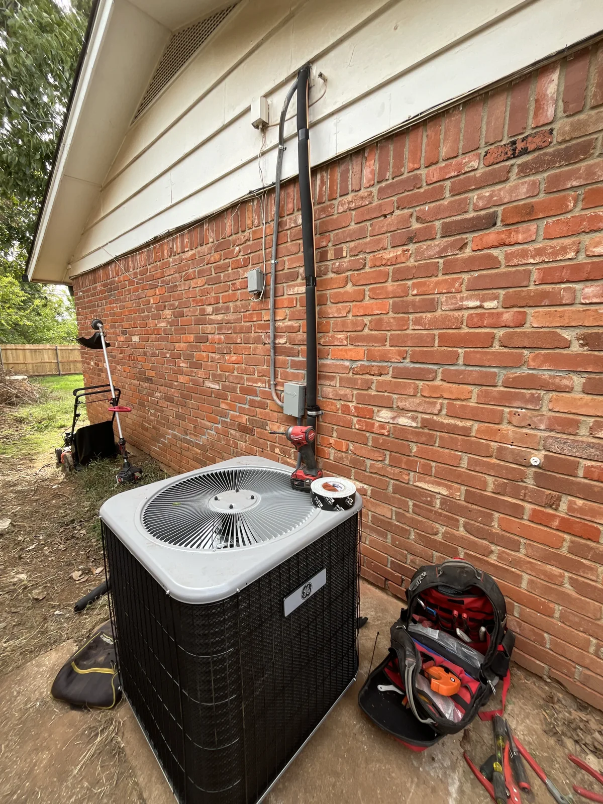 New General Electric outdoor unit and insulated line set installed at an Edmond home