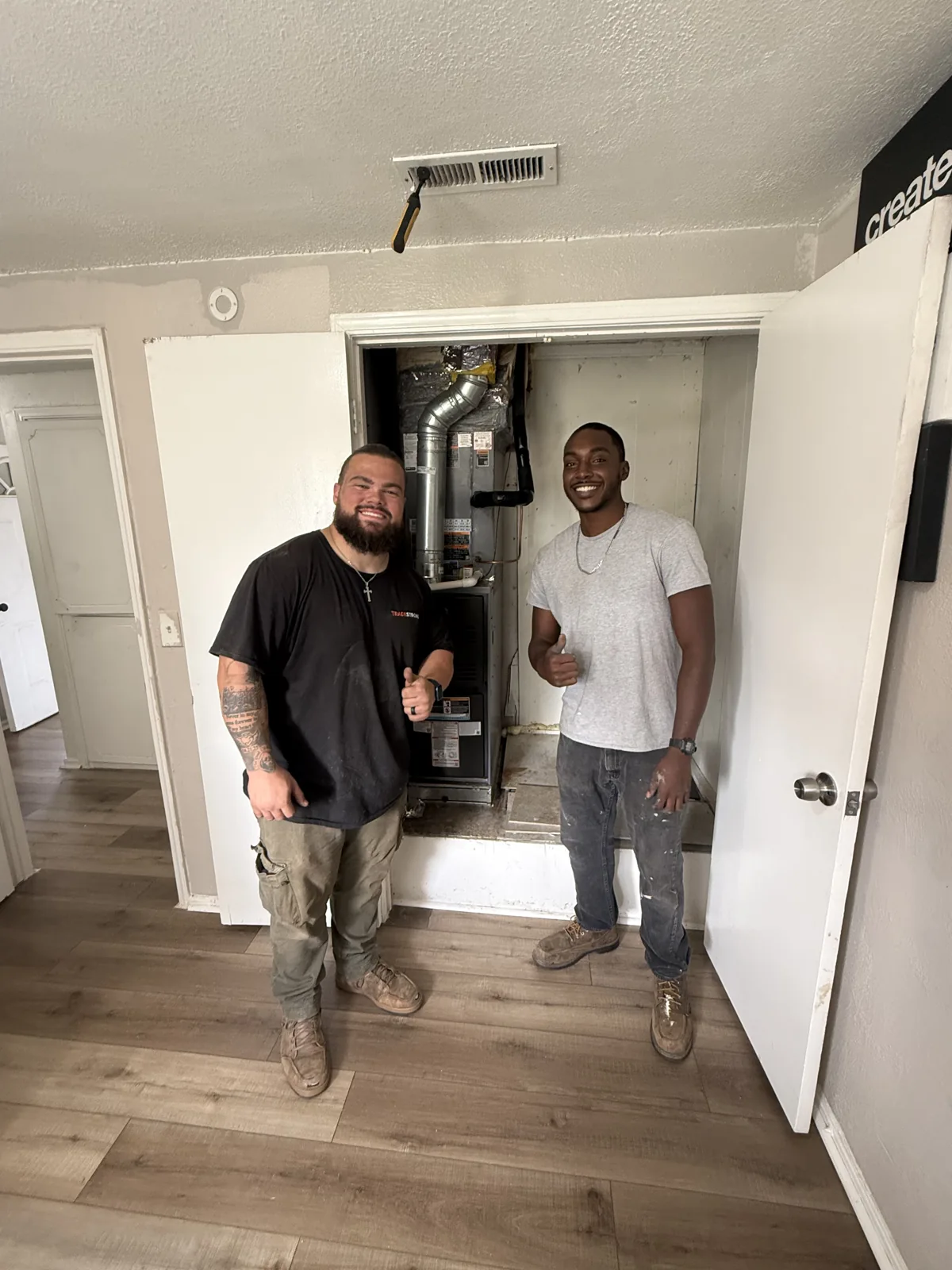 Two TradeStrong installers standing beside the indoor HVAC equipment at the Edmond project