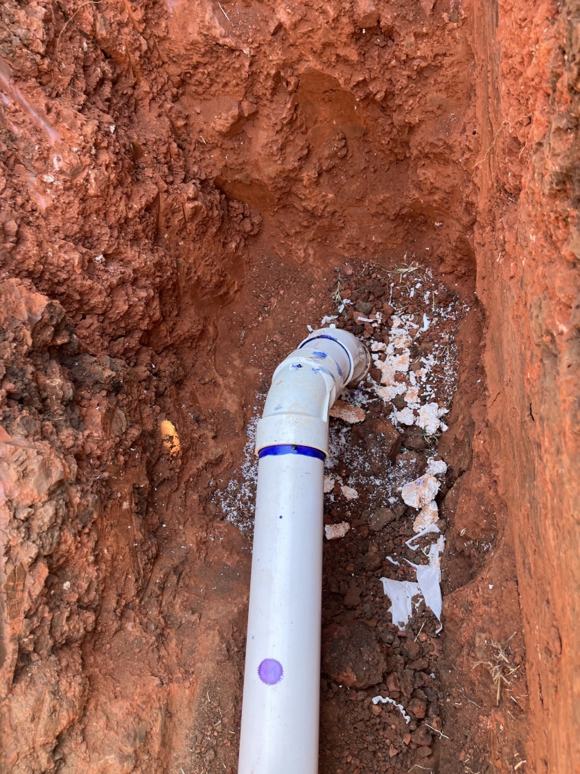 Replacement sewer piping visible in the open trench.