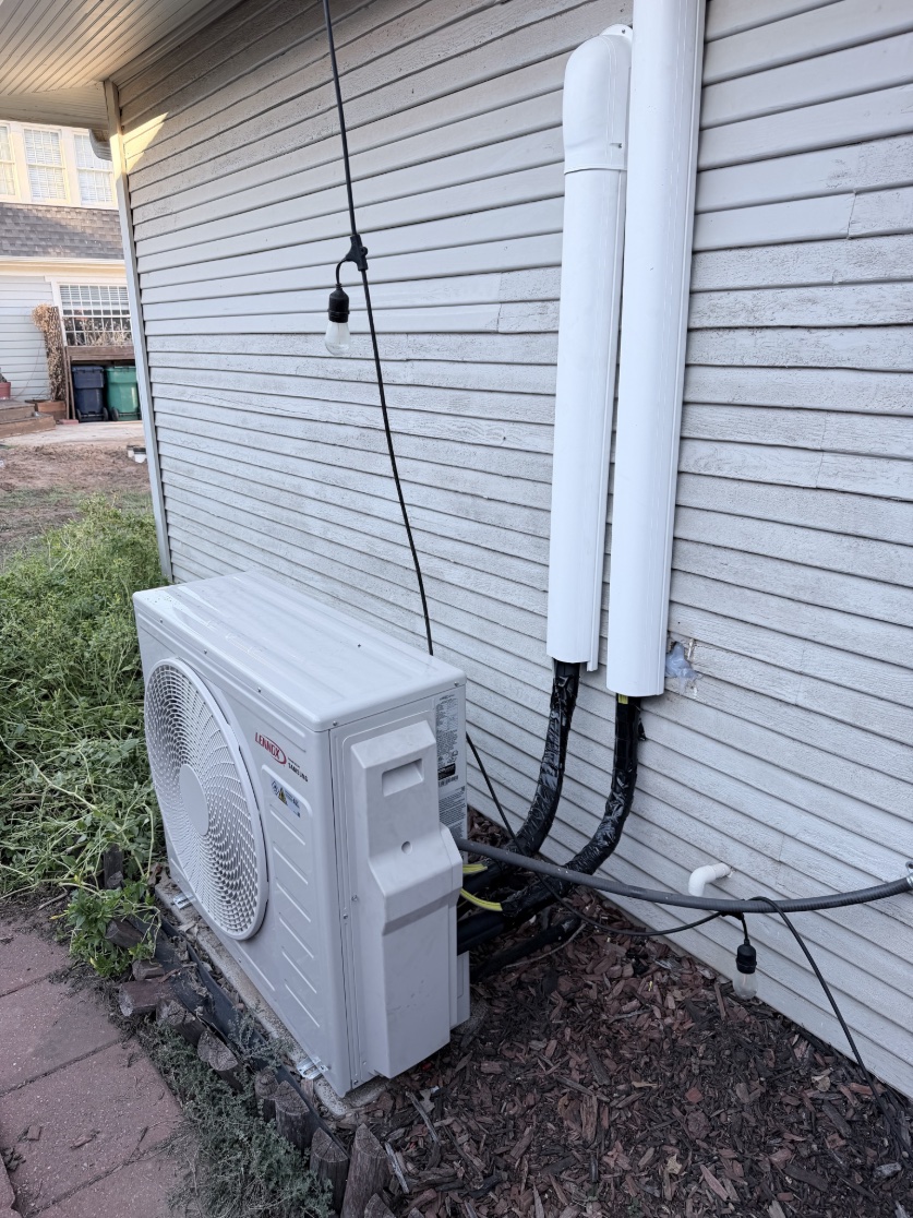 Outdoor mini-split unit beside an older Heritage Hills OKC building with two vertical white line-set covers