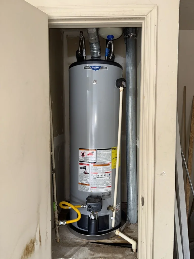 New GE RealMAX gas water heater installed in a Midwest City utility closet with a drain pan and expansion tank above