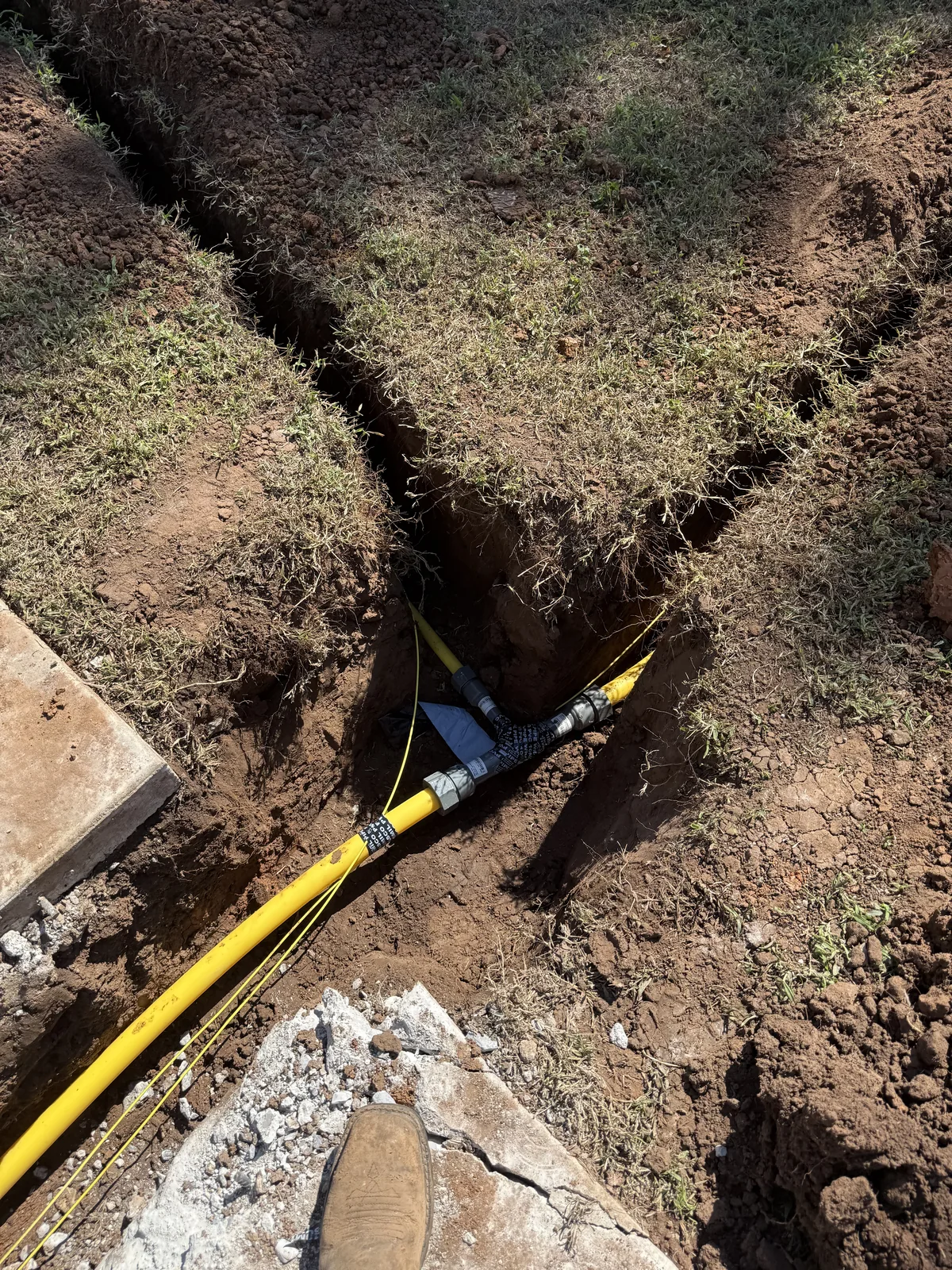 Branch connection joining new yellow gas piping in the excavated trench